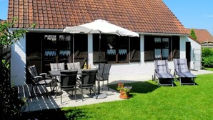 A house with a tiled roof, a covered patio with outdoor furniture, and a lawn. - Seagull's Nest Modern Retreat (De Panne)