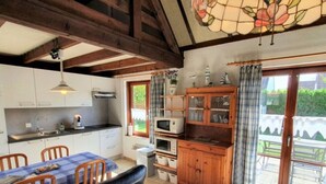 A cozy kitchen with a dining area, wooden cabinets, and a large window with curtains. - Seagull's Nest Modern Retreat (De Panne)