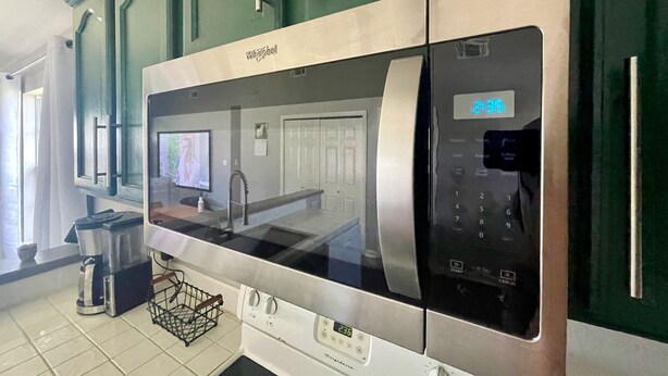 A kitchen with a stainless steel microwave oven, a coffee maker, and a small trash bin. - Home Theatre with King Bed (Alpine)