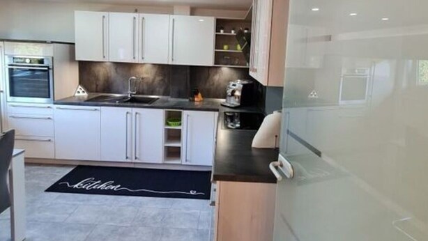 Una cucina moderna con mobili bianchi, un piano di lavoro nero e un forno integrato.