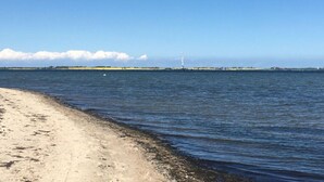A beach with a lighthouse in the distance, calm water, and a clear sky. - Holiday Home Aunt Emma (Zierow)
