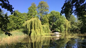 A tranquil pond with weeping willow trees and a small gazebo. - Holiday Home Aunt Emma (Zierow)