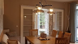 Un coin repas avec une table et des chaises en bois, un lustre et un canapé agrémenté de coussins.