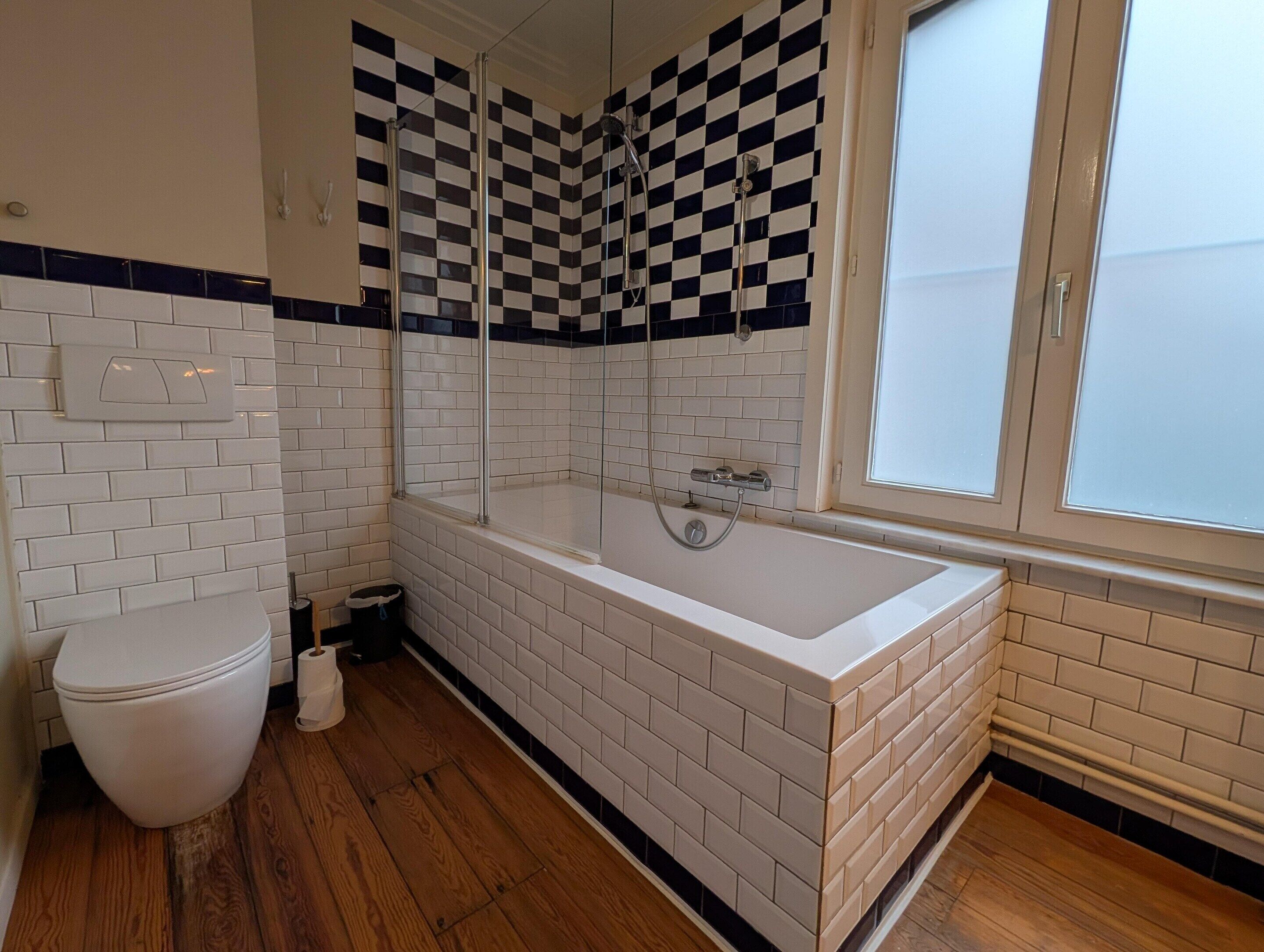 A bathroom with a white bathtub, a toilet, and a shower enclosure.