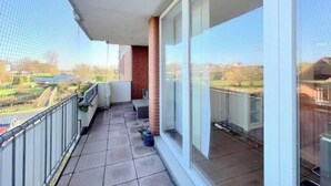 A balcony with a view of a residential area, a tiled floor, and a metal railing. - Nelly Modern Retreat (Wangerland)