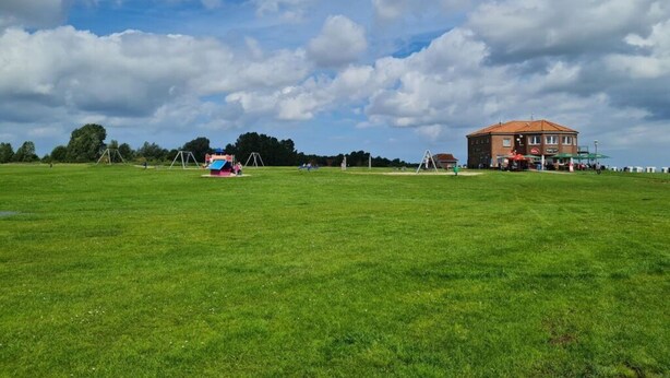 A large grassy field with a building in the distance. - Nelly Modern Retreat (Wangerland)