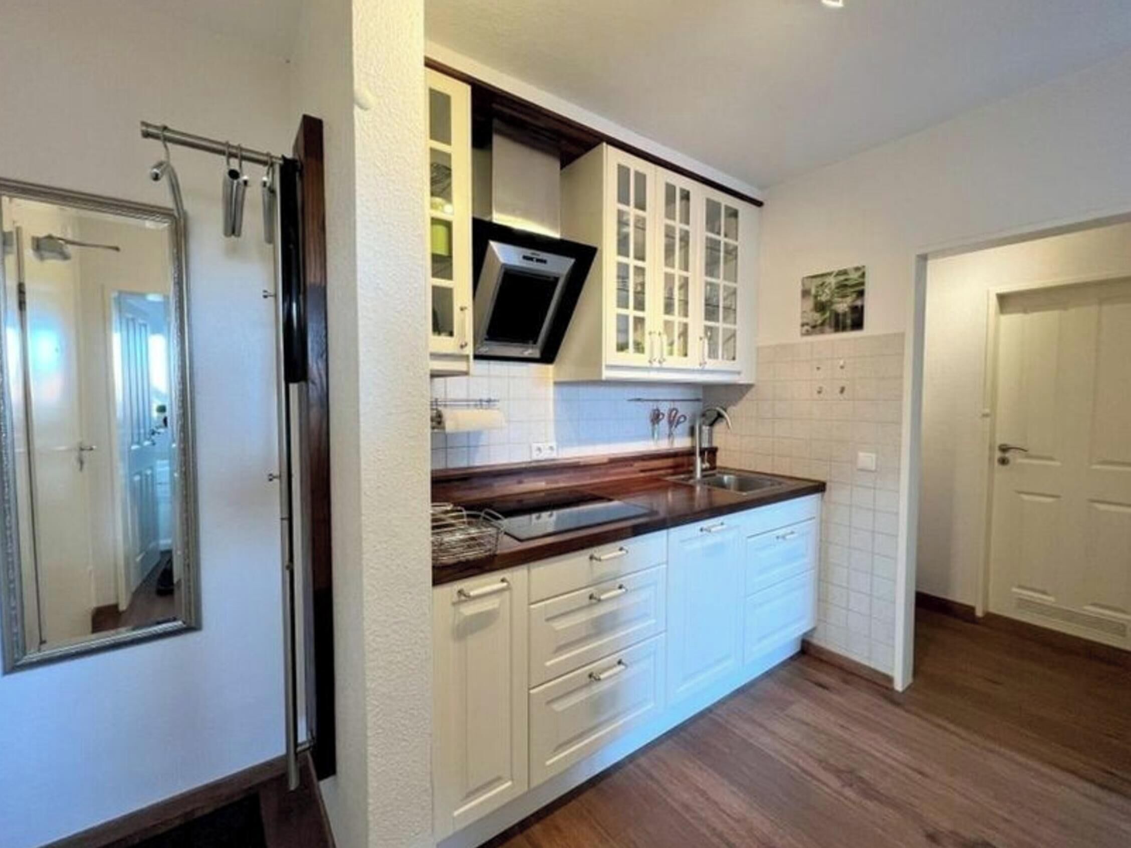 A kitchen with white cabinets, a wooden countertop, and a built-in microwave.