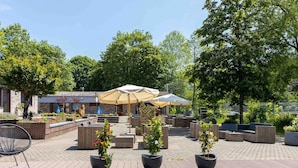 An outdoor patio area with wooden flooring, seating arrangements, and potted plants. - Bungalow in Waxweiler Near Nature Trails (Waxweiler)