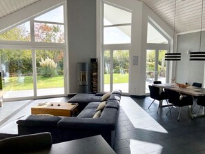 A spacious living area with a large sofa, a dining table with chairs, and a fireplace. - Ufer 7 Comfortable Holiday Residence (Trent)