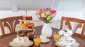 A breakfast table with a fruit platter, pastries, a vase of flowers, and coffee and juice cups. - Secret Apartments - One Bedroom Apartment (Dubrovnik)