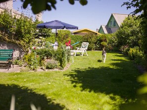 A well-maintained garden with a lawn, a bench, and a chair. - "de Zeehond" Strandslag (Julianadorp)