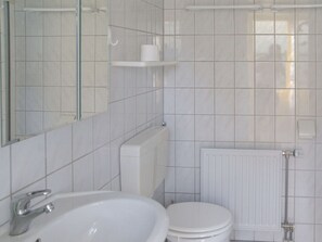 A bathroom with a white sink, toilet, and a mirror. - "de Zeehond" Strandslag (Julianadorp)