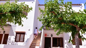 A white building with a staircase leading to a door, a table with chairs, and a tree with green leaves. - Belvilla by OYO Torreblanca I Primera Planta (Torreblanca)