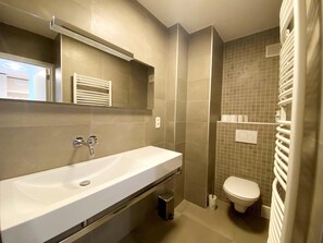 Een moderne badkamer met een ruime wastafel, een spiegel, een toilet en een handdoekhouder.