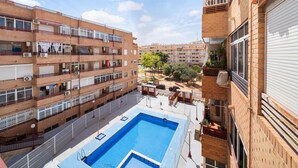 A multi-story building with a rooftop pool, balconies with railings, and a clear view of the surrounding area.