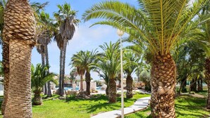 A pathway lined with palm trees and a pool area in the background. - Belvilla by OYO Macael (Roquetas de Mar)