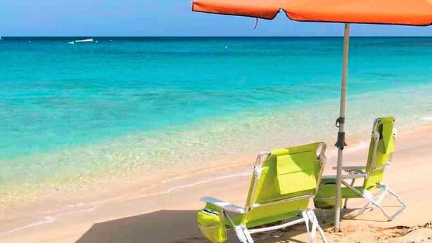 A beach scene with two green lounge chairs and an orange umbrella. - Belvilla by OYO Macael (Roquetas de Mar)
