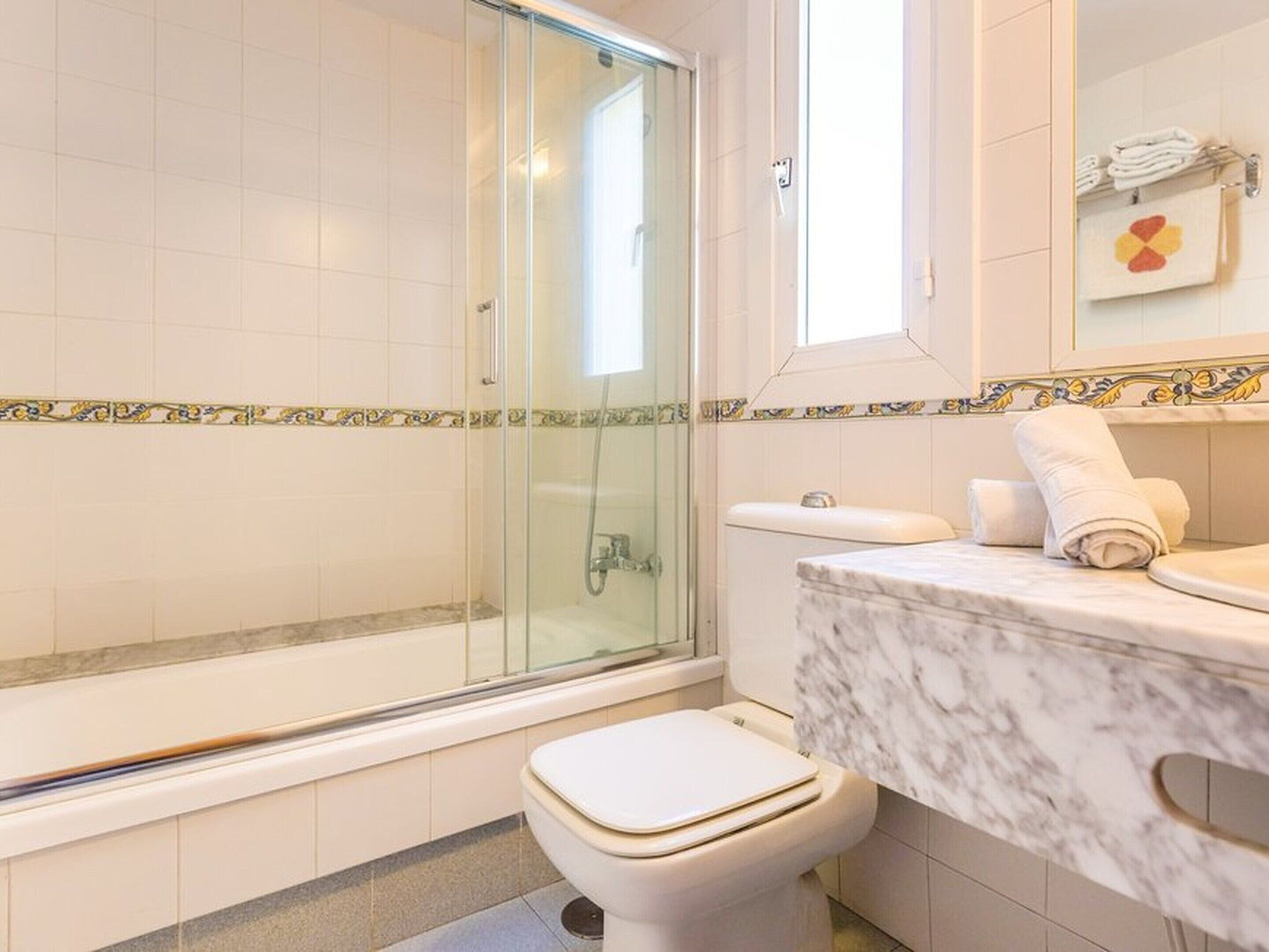 Ein Badezimmer mit Duschkabine, Toilette und Marmorwaschbecken mit Handtuchhalter.
