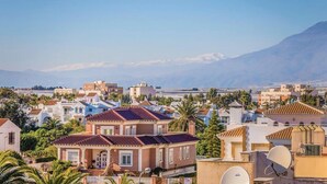 A residential area with houses, some with satellite dishes, and a mountain in the background. - Belvilla by OYO Macael (Roquetas de Mar)