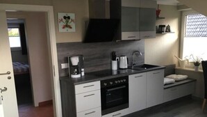 A compact kitchen with a built-in oven, a coffee maker, and a sink. - Seagull Modern Retreat (Wangerland)