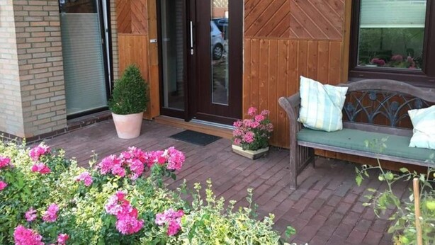 A wooden exterior with a glass door, a bench, and potted plants. - Seagull Modern Retreat (Wangerland)