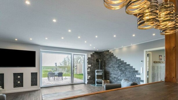 A modern living room with a large TV, a fireplace, and a staircase leading to another level.