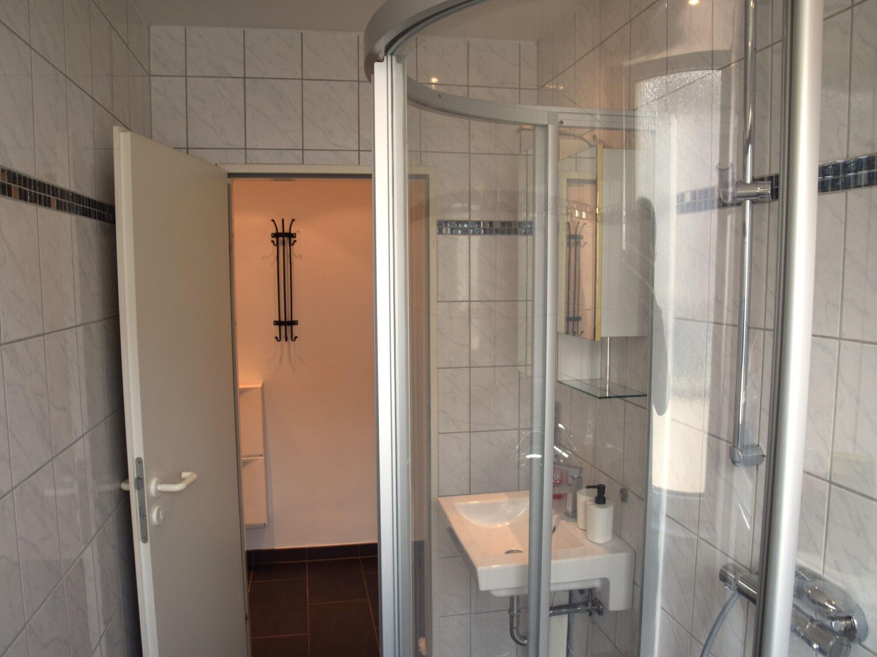 Ein modernes Badezimmer mit Duschkabine aus Glas, einem weißen Waschbecken und einem Spiegel.