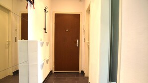 A hallway with a wooden door, a white refrigerator, and a tiled floor. - Cosy Apartment in Oberhausen With Balcony (Oberhausen)