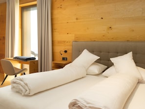 Relax in a spacious room with a large bed, desk, and window with curtains.