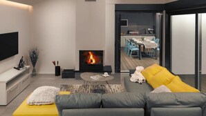 A modern living room with a fireplace, a sofa, a coffee table, and a TV mounted on the wall.