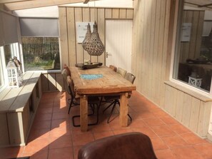 Ein Holzespeisesaal mit Stühlen, einer Hängeleuchte und Blick ins Freie.