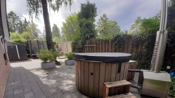 A patio area with a hot tub, wooden steps, and a seating bench. - Holiday Home in Voorthuizen With Hot Tub (Voorthuizen)