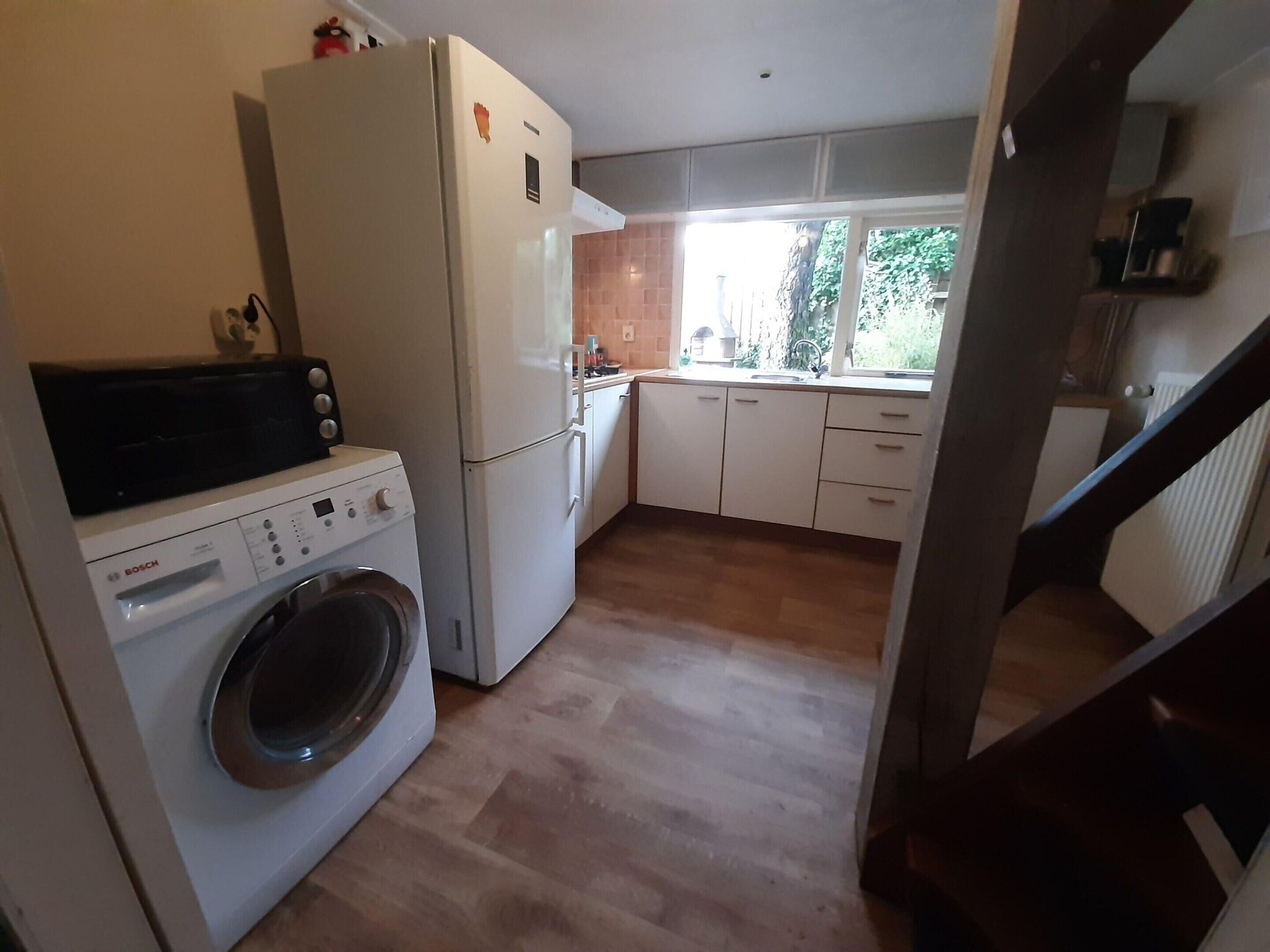 A compact kitchen with a washing machine, a refrigerator, and a sink.
