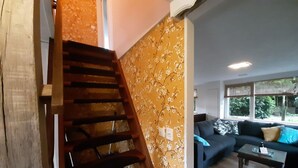 A staircase with wooden steps leading to a living area with a sofa and a coffee table. - Holiday Home in Voorthuizen With Hot Tub (Voorthuizen)