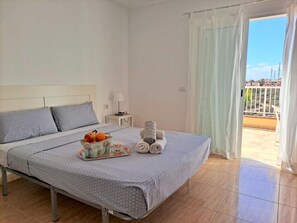Relax in comfort with a neatly made bed, a bedside table, and a balcony door offering a view of the outside.