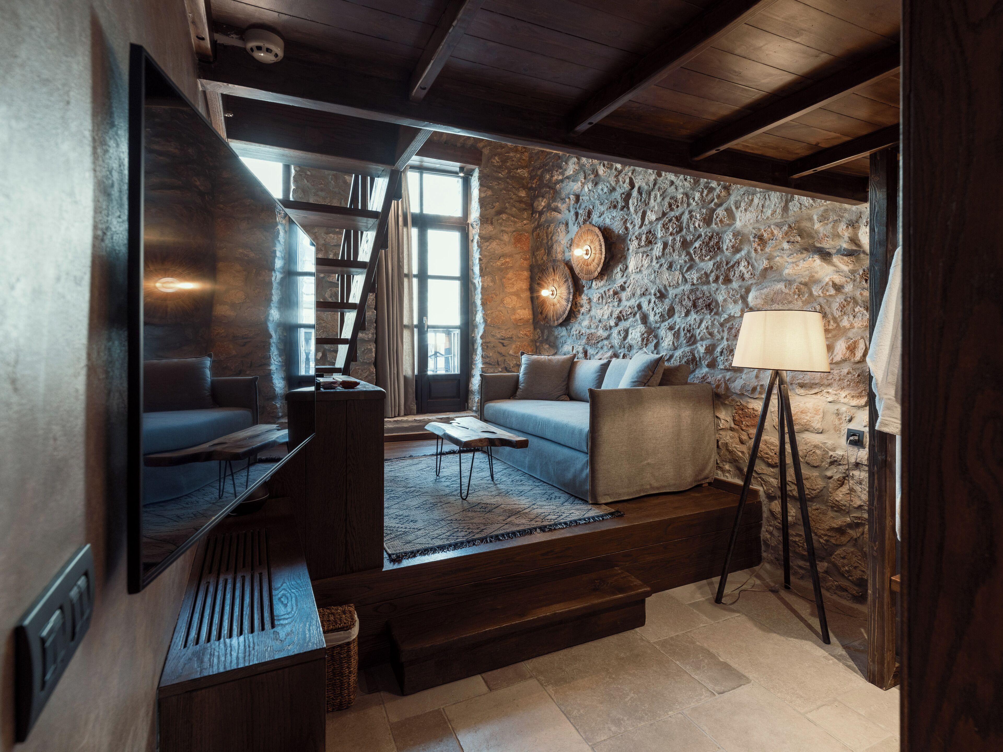 A cozy living room with a stone wall, a sofa, a coffee table, and a lamp.