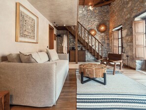 Ein gemütliches Wohnzimmer mit Steinwand, Holzboden und einer großen Couch.
