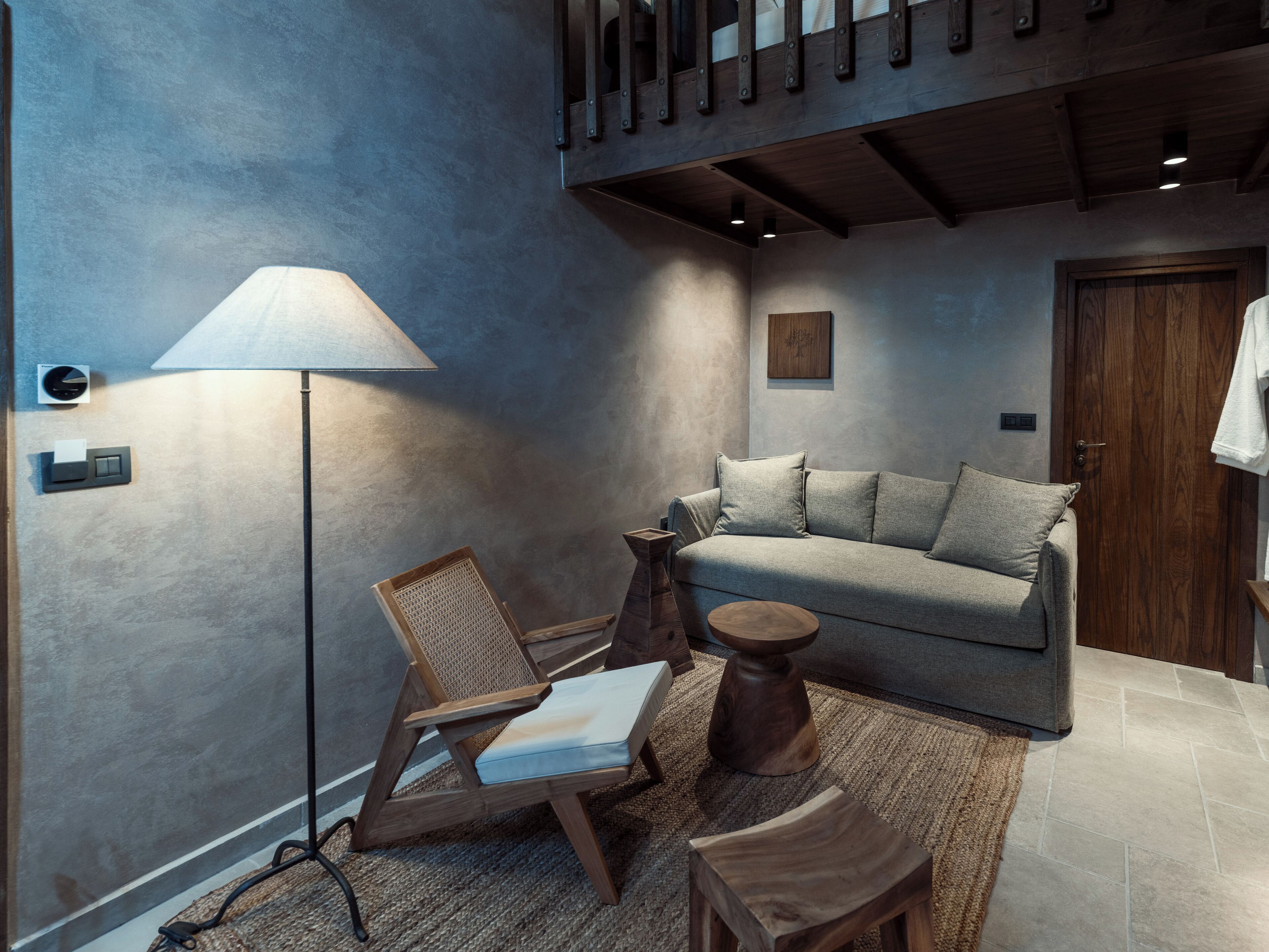 A modern living room with a sofa, a wooden chair, a floor lamp, and a small wooden table.