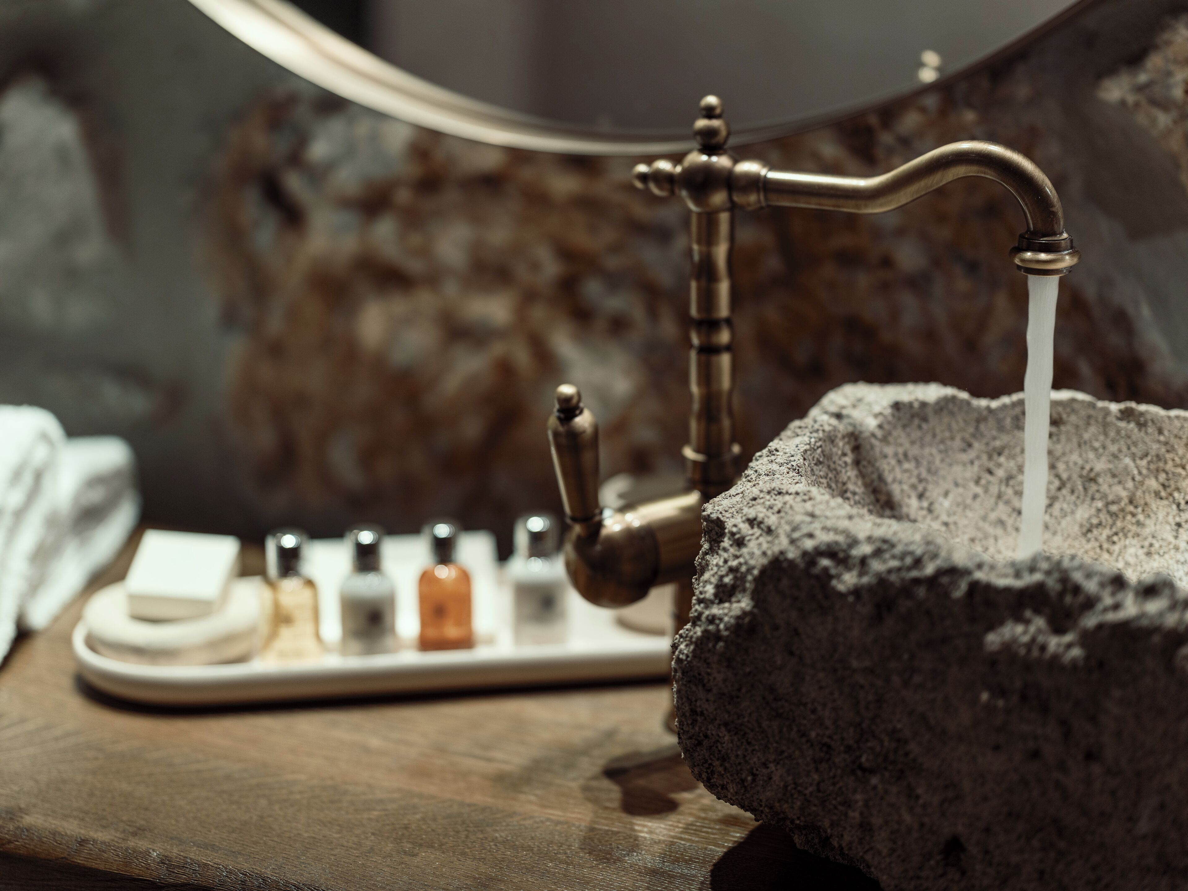 Un lavabo de piedra con un grifo antiguo y agua corriendo.