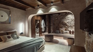 Un dormitorio con una cama grande, una pared de piedra y un techo de madera.