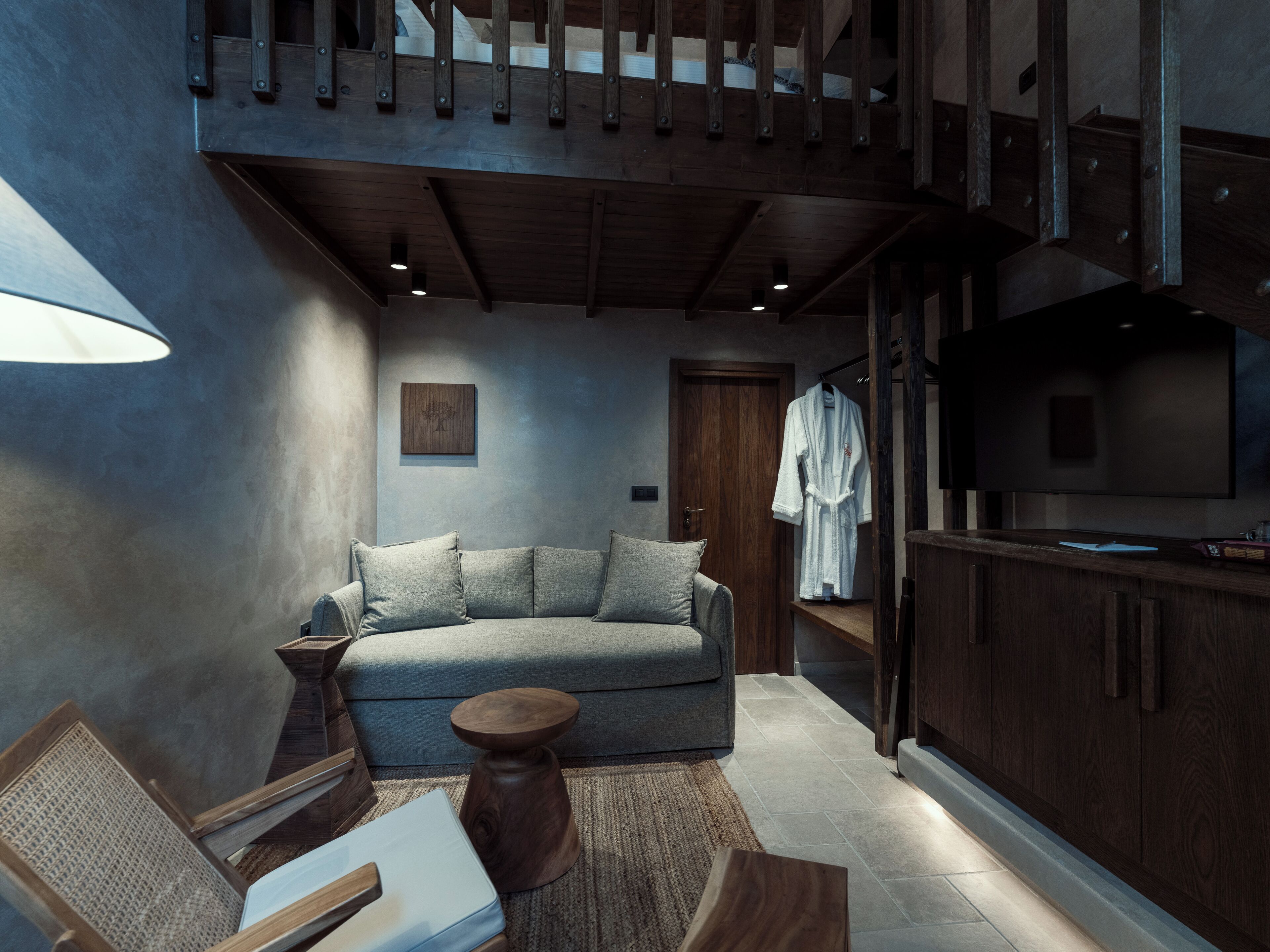 A modern living room with a grey sofa, wooden coffee table, and a television on a wooden cabinet.