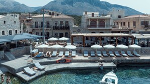 Un hotel en la costa con aguas cristalinas, tumbonas y una zona junto a la piscina.