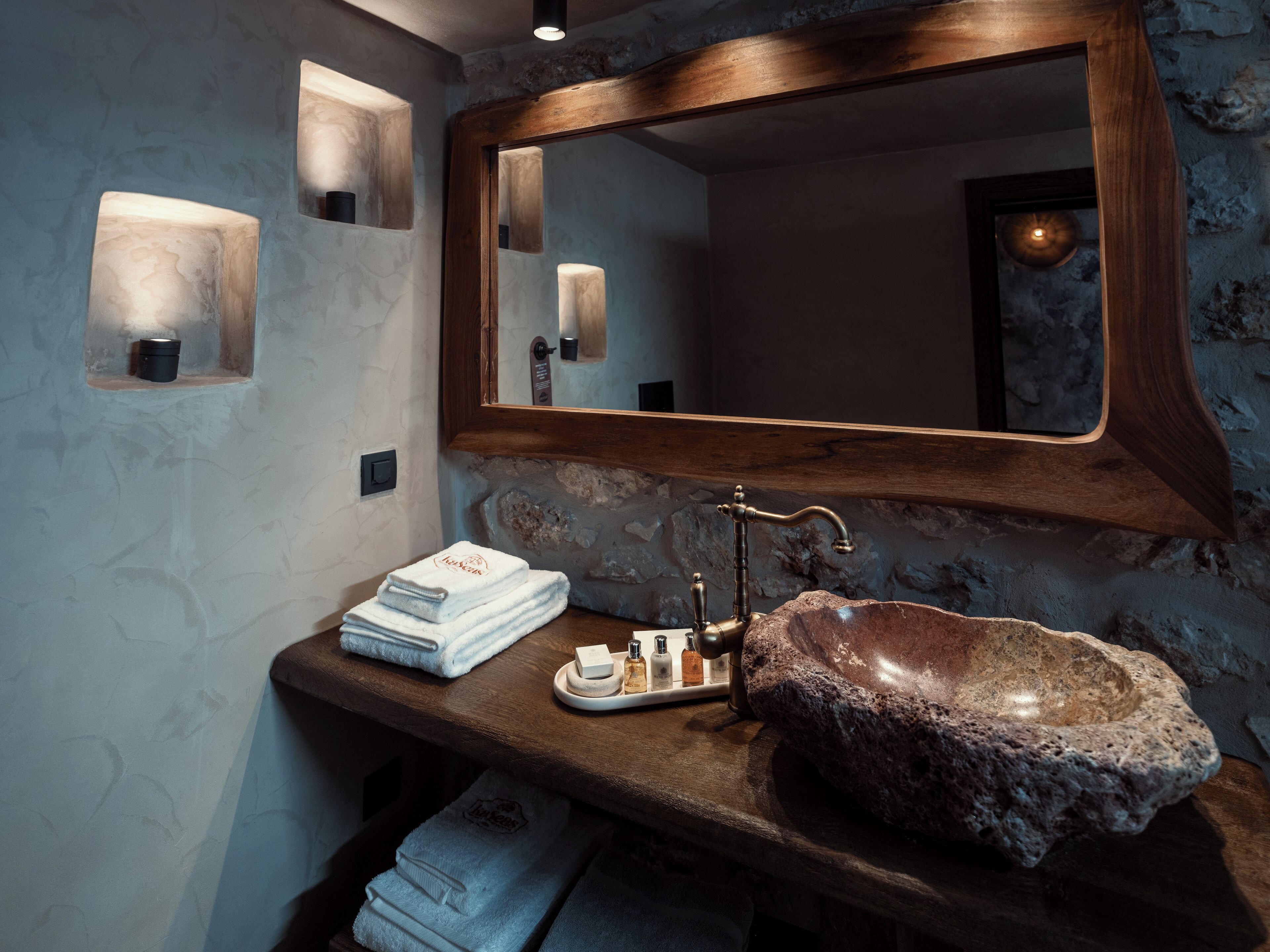 Un baño con un lavabo de piedra, encimera de madera y un espejo sobre el lavabo.