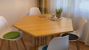A dining area with a wooden table, four chairs, a potted plant, and a modern pendant light. - Holiday Apartment Luna (Ruedesheim am Rhein)