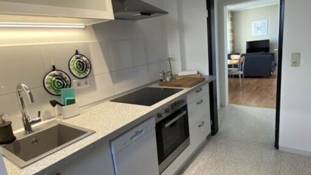 A modern kitchen with white cabinetry, a stainless steel sink, and a built-in oven. - Holiday Apartment Luna (Ruedesheim am Rhein)