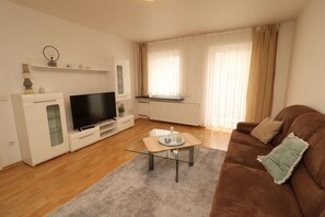 Relax in this stylish living room with a flat-screen TV, glass coffee table, and comfortable sofa.