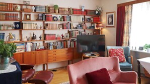 A cozy living room with a bookshelf, a television, and comfortable seating. - 5 Person Holiday Home in Risor (Risør)