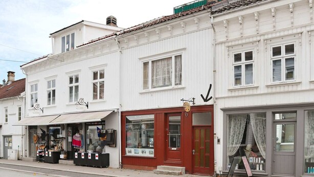 A street view of a row of white buildings with various shops and businesses.