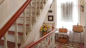 A staircase with white balusters and a red handrail, leading to a room with a white table, wicker baskets, and a vase with sunflowers. - 5 Person Holiday Home in Risor (Risør)