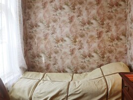 Una stanza con un letto, un comodino in legno e carta da parati floreale.